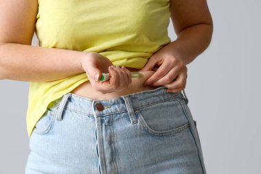 Şeker hastası bir kadın gri arka planda tükenmez kalem kullanıyor, yakın plan.