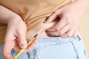 Şeker hastası bir kadın kendine insülin enjekte ediyor.