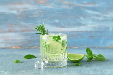 Mavi arka planda bir bardak lezzetli mojito.