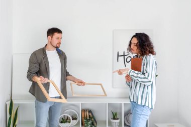 Genç çift evde çerçevelerini asıyor.