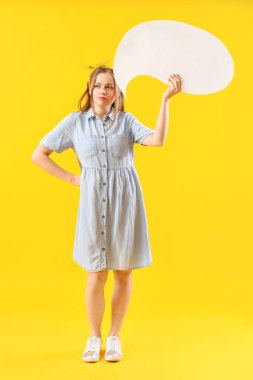 Sarı arka planda boş konuşma balonu olan düşünceli genç bir kadın.