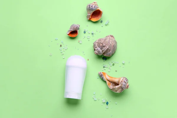 Deodorant with shells and sea salt on light green background