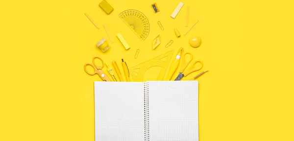 Empty notebook and set of school supplies on yellow background