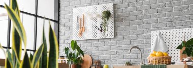 Gri tuğla duvarda asılı modern tahtalar olan mutfak.