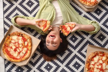 Kutular dolusu lezzetli pizzayla yerde yatan mutlu genç bir kadın.