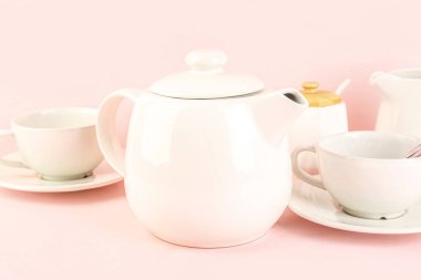 Çaydanlık ve fincanlar pembe arka planda, yakın plan
