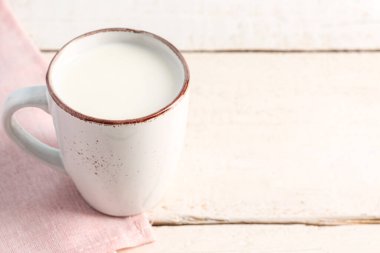 Beyaz ahşap masada taze sütle dolu bir fincan.