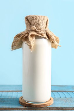 Mavi ahşap masada taze süt şişesi.