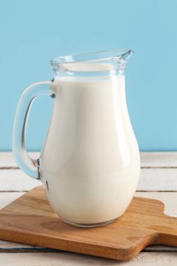 Beyaz ahşap masada taze sütle sürahi.