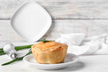 Hafif ahşap zemin üzerinde lezzetli etli turta tabağı.