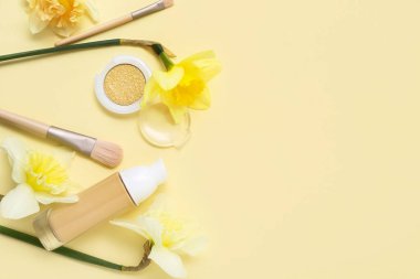 Soluk sarı arka planda farklı kozmetik ürünleri olan güzel nergisler.