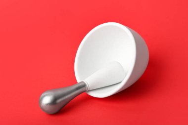 Kırmızı arkaplanda havan ve tokmak