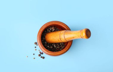 Ahşap harç ve ahşap, mavi arka planda karabiber.