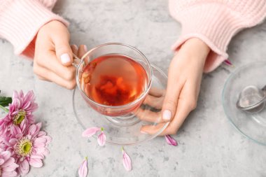 Bir fincan çay ve mermer masada güzel kasımpatı taşıyan kadın elleri.