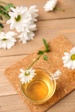 Ahşap masada kasımpatı dolu bir bardak çay.