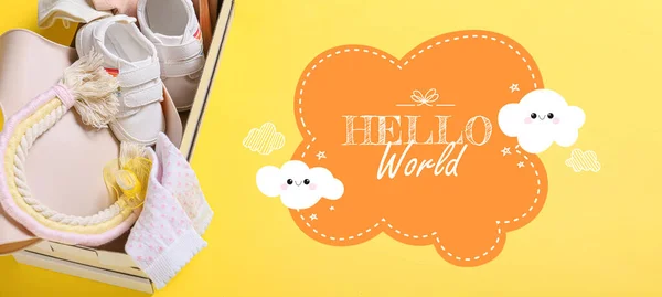Banner with text HELLO WORLD, baby clothes and accessories in box