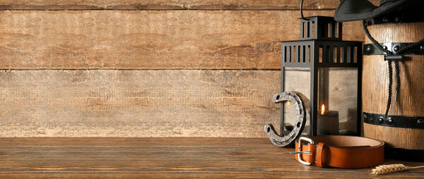 Ковбойская шляпа с бочкой, лентой, подковы и ремнем на деревянном фоне с пространством для текста