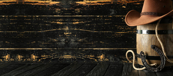 Ковбойская шляпа с бочкой, подковы и так далее на темном деревянном фоне с пространством для текста