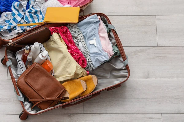明るい木製の床に服を着たオープンスーツケース — ストック写真