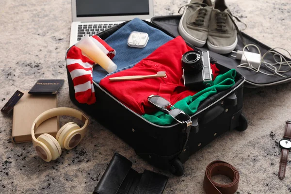 Koffer Mit Männerkleidung Laptop Und Reiseaccessoires Auf Farbigem Teppich — Stockfoto