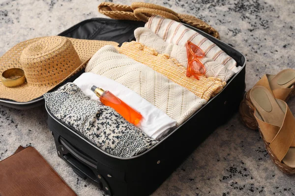 Suitcase with summer clothes and accessories on color carpet