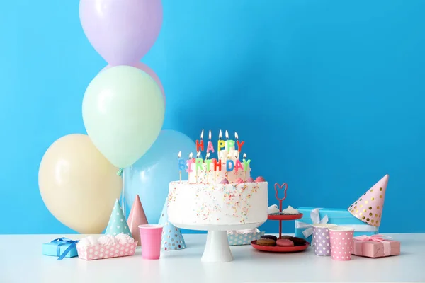 蓝墙附近桌子上有不同甜食的生日蛋糕 — 图库照片