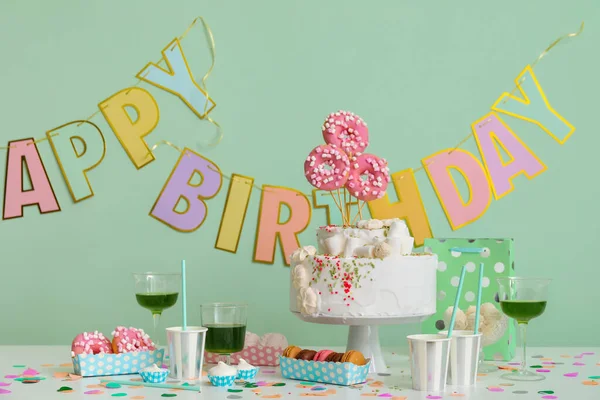 Tort Urodzinowy Różnymi Słodyczami Stole Przy Zielonej Ścianie — Zdjęcie stockowe