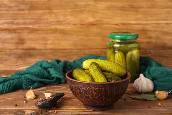 stock image Jar and bowl with tasty canned cucumbers on wooden table