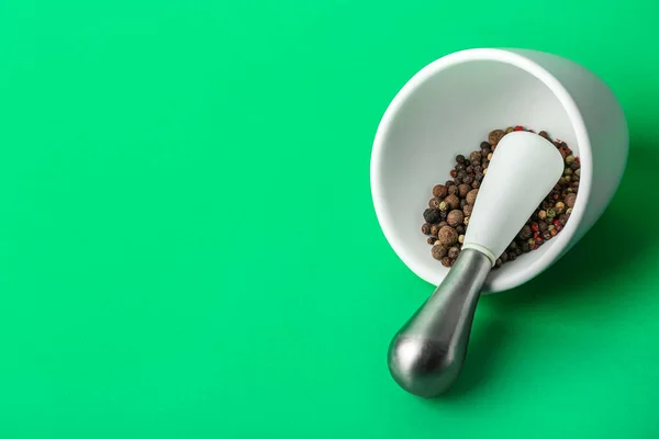 stock image Mortar and pestle with peppercorns on green background