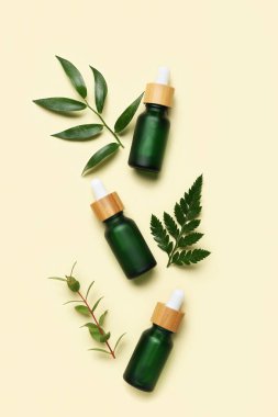 Bej arka planda bitki dalları olan kozmetik yağı şişeleri