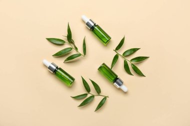 Bej arka planda bitki dalları olan kozmetik yağı şişeleri
