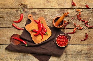 Kahverengi ahşap zemin üzerinde havan topu olan taze ve kuru kırmızı biber panosu.