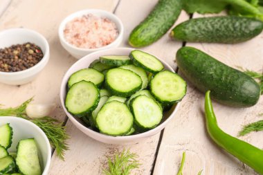 Hafif ahşap arka planda taze salatalık parçalarıyla dolu bir kase.