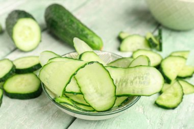 Hafif ahşap arka planda taze salatalık dilimleri ile kase