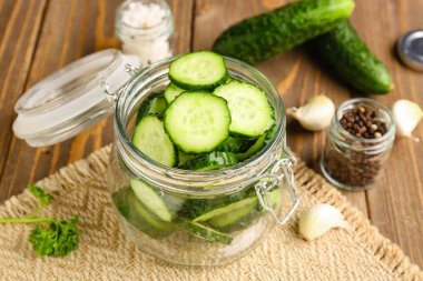 Ahşap arka planda taze kesilmiş salatalıklı kavanoz.