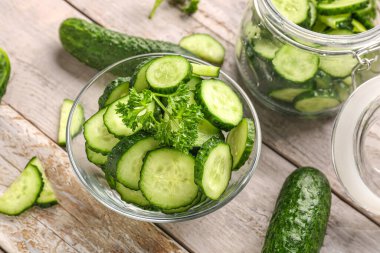 Hafif ahşap zemin üzerinde taze kesilmiş salatalıklarla dolu bir kase.