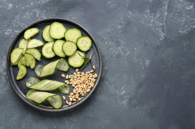 Yeşil arka planda taze salatalık ve fındıklı tabak.