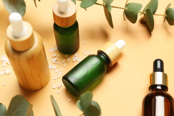 Butelki Olejku Kosmetycznego Gałązki Eukaliptusa Pomarańczowym Tle — Zdjęcie stockowe