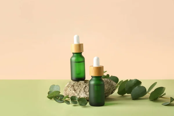 Flaskor Med Kosmetisk Olja Med Eukalyptusgrenar Och Sten Grönt Bord — Stockfoto