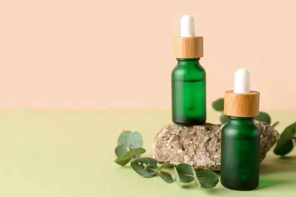 Flaschen Kosmetiköl Mit Eukalyptuszweigen Und Stein Auf Grünem Tisch — Stockfoto
