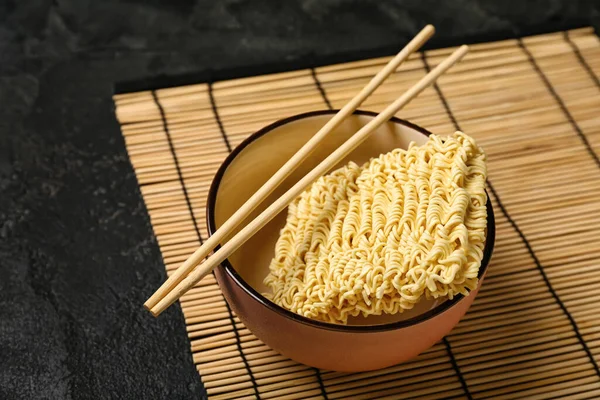 生方便面 筷子和竹垫 背景为黑色 — 图库照片