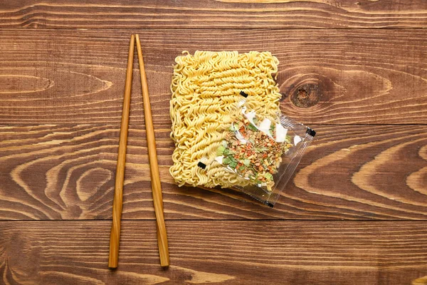 用调料和筷子在木制背景上煮方便面 — 图库照片