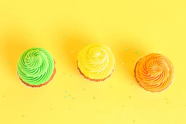 黄色の背景においしいカラフルなカップケーキ — ストック写真