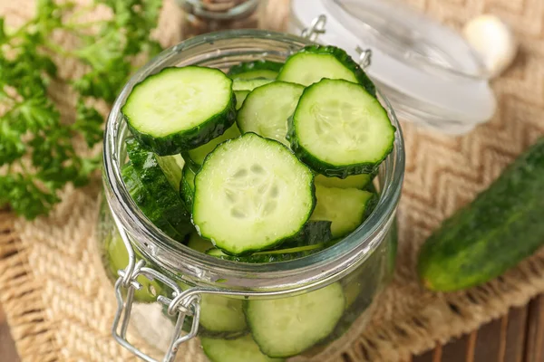 stock image Jar with fresh cut cucumber on table, closeup