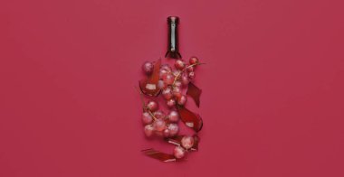 Kırık cam şarap şişesi ve mor arka planda olgun üzümler. Tasarım için pankart
