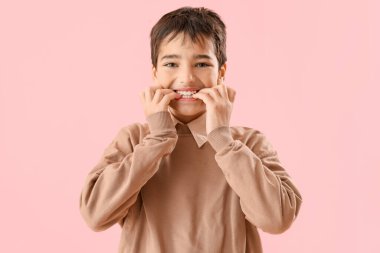 Pembe arka planda tırnaklarını yiyen küçük çocuk.