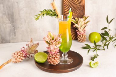 Bir bardak kokteyl ve grunge duvarının yanındaki masada küçük ananas ve limon.