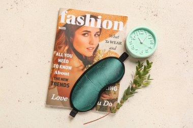 Uyku maskesi, alarm saati ve ışık arka planında şarjör.