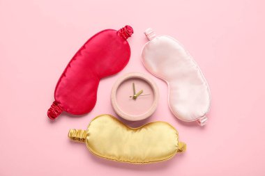 Pembe arka planda uyku maskeleri ve çalar saat