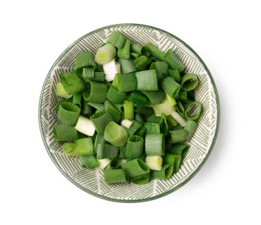 Beyaz arka planda taze kesilmiş yeşil soğanlı kase